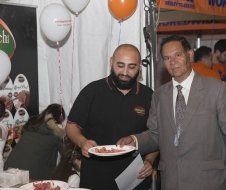 Two men are standing next to each other and one is holding a plate of food