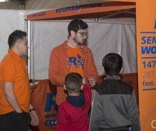 A group of people are standing in front of an orange tent.