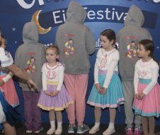 A group of children are standing next to each other in front of a sign that says festival.