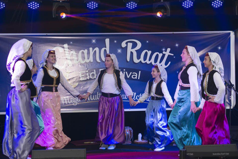 A group of people are dancing in front of a sign that says raat