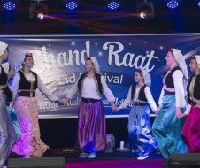 A group of people are dancing on a stage at a festival.