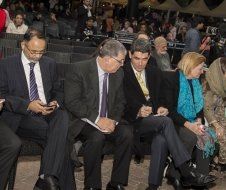 A group of people in suits and ties are sitting in a row.