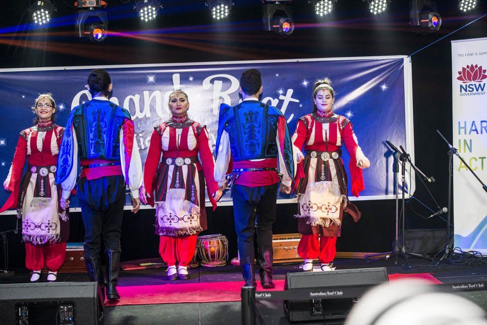 A group of people are standing on a stage holding hands.