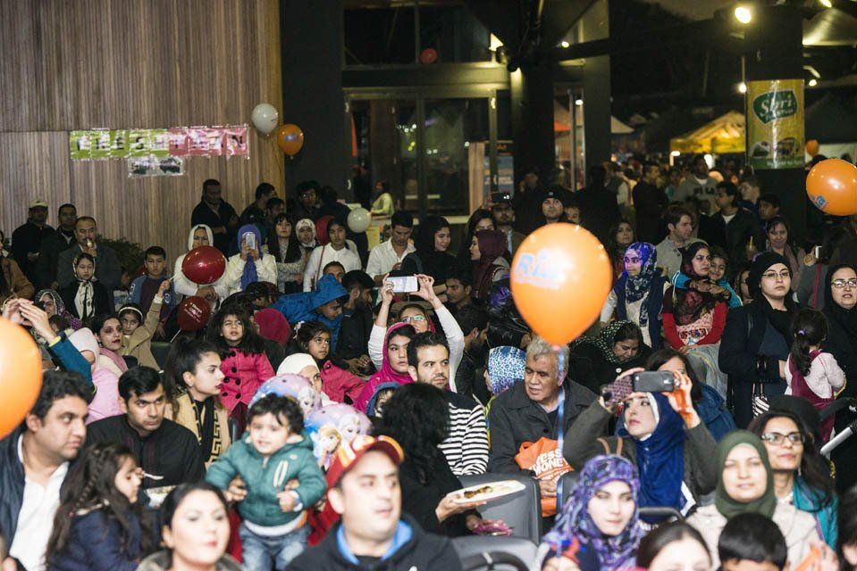 A large group of people are sitting in a room with balloons.