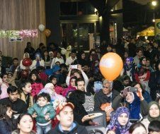 A large group of people are sitting in a room holding balloons.