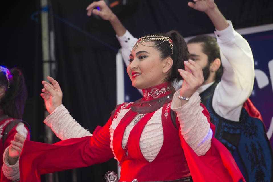 A woman in a red dress is dancing with a man in a blue vest.