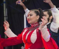A woman in a red dress is dancing with a man in a black vest.