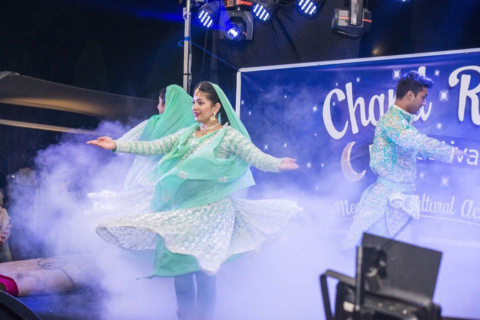 A group of people are dancing on a stage in front of a sign.