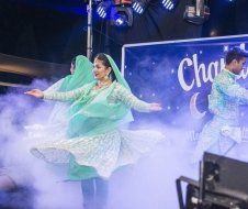 A group of people are dancing on a stage in front of a sign.