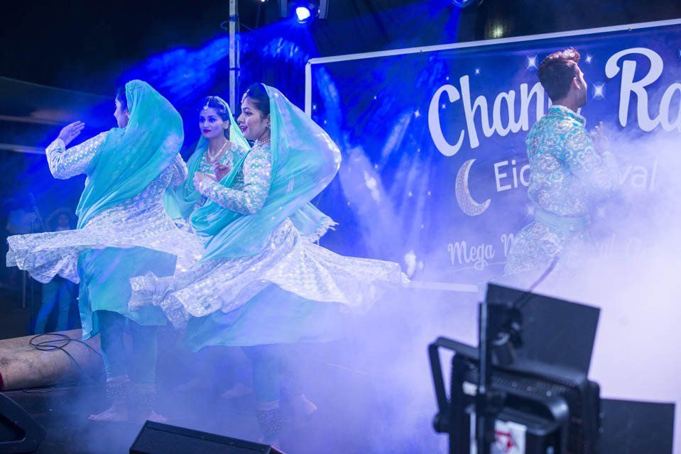 A group of women are dancing on a stage in front of a sign.