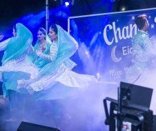 A group of women are dancing on a stage in front of a sign.