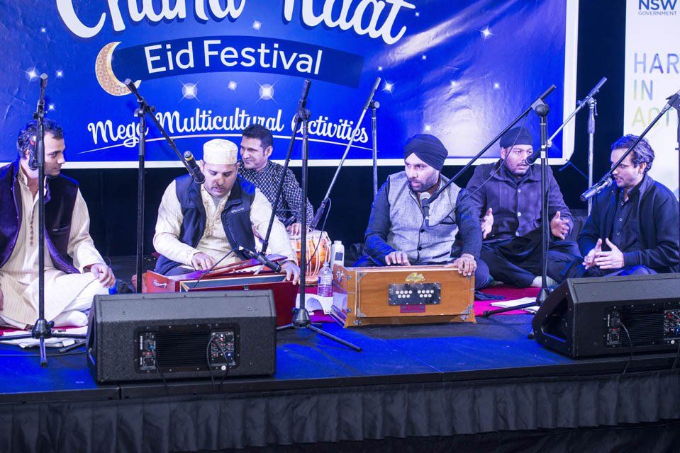 A group of men are sitting on a stage playing instruments.