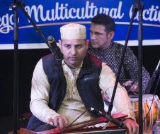 A man is playing a musical instrument in front of a microphone.