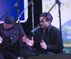 Two men are sitting in front of microphones on a stage.