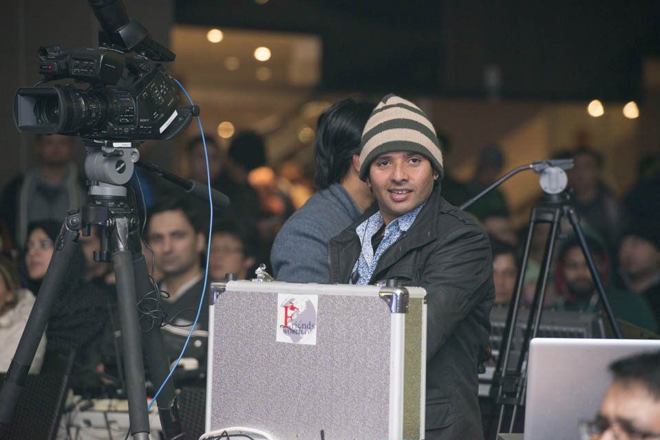 A man in a hat is standing in front of a camera.