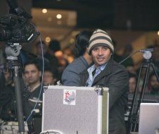 A man in a striped hat is standing in front of a camera.