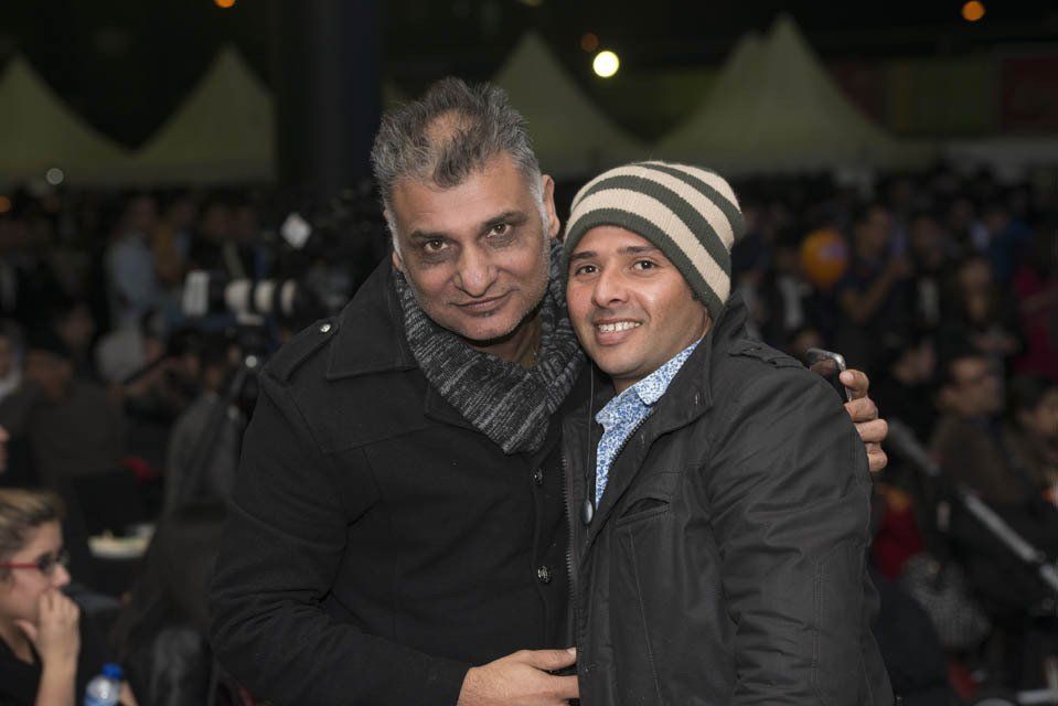 Two men are posing for a picture in front of a crowd