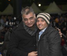 Two men are posing for a picture together and one of them is wearing a hat.