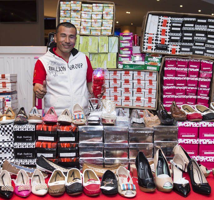 A man standing in front of a display of shoes with boxes of shoes behind him