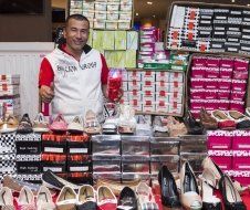 A man is standing in front of a display of shoes and giving a thumbs up.