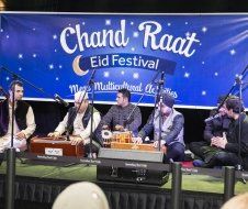 A group of men are sitting on a stage playing instruments.