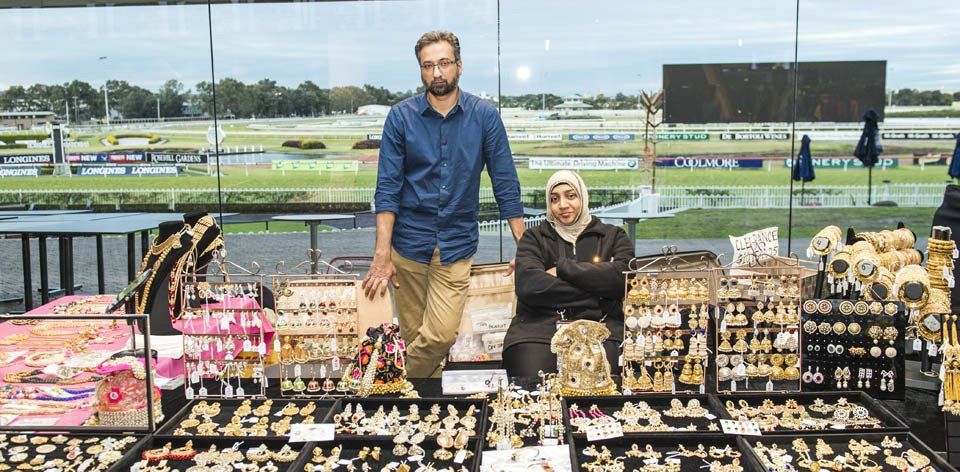 A man and a woman are standing in front of a display of jewelry.