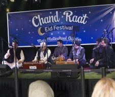 A group of men are playing instruments on a stage at a festival.