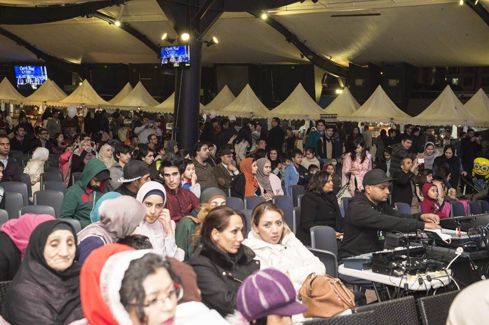 A large group of people are sitting in a stadium watching a concert.