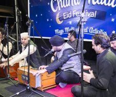 A group of men are sitting on the floor playing instruments in front of microphones.