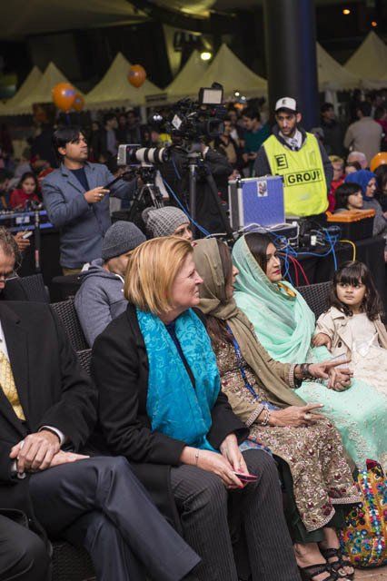 A woman in a blue scarf sits in a crowd of people