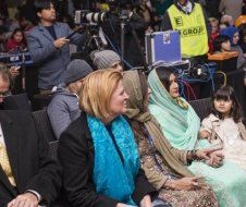 A group of people are sitting in a row in front of a camera.