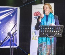 A woman is standing at a podium holding a microphone.