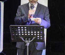 A man in a suit and tie is standing at a podium holding a microphone.