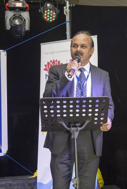A man in a suit and tie is standing at a podium speaking into a microphone.