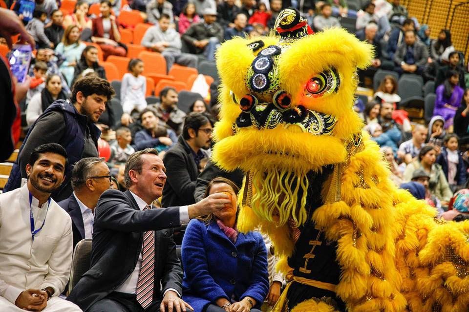 A group of people are sitting in a stadium watching a lion costume perform.
