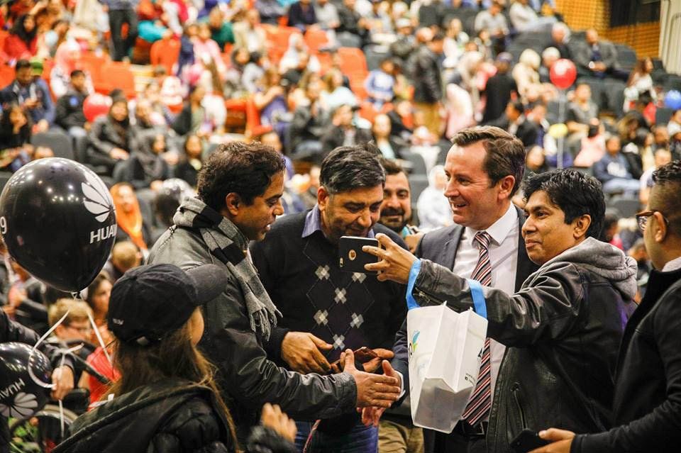 A group of people are standing in front of a crowd in an auditorium.