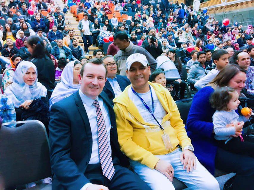 A man in a suit and tie is sitting in a crowd of people