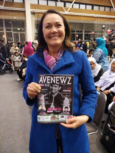 A woman in a blue coat is holding a copy of avenewz