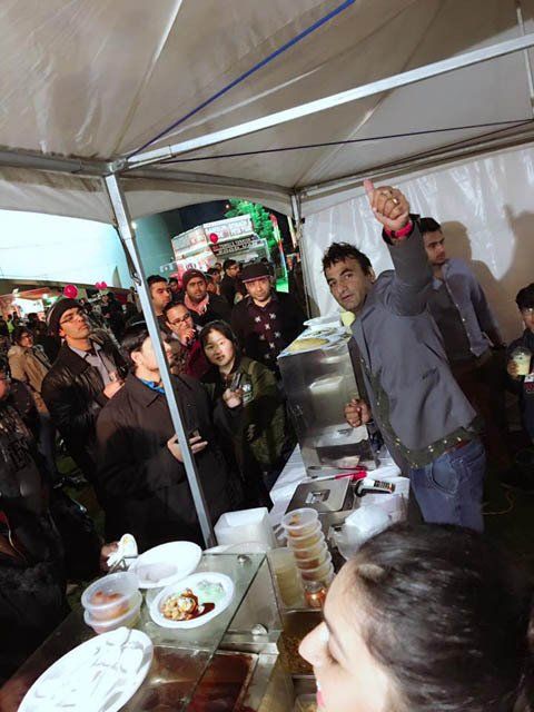 A group of people are gathered under a tent eating food.