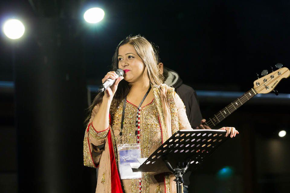 A woman is singing into a microphone on a stage.