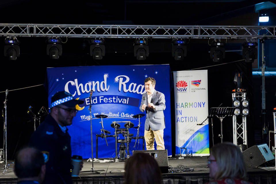 A man stands on a stage in front of a sign that says ' chard rao ' on it