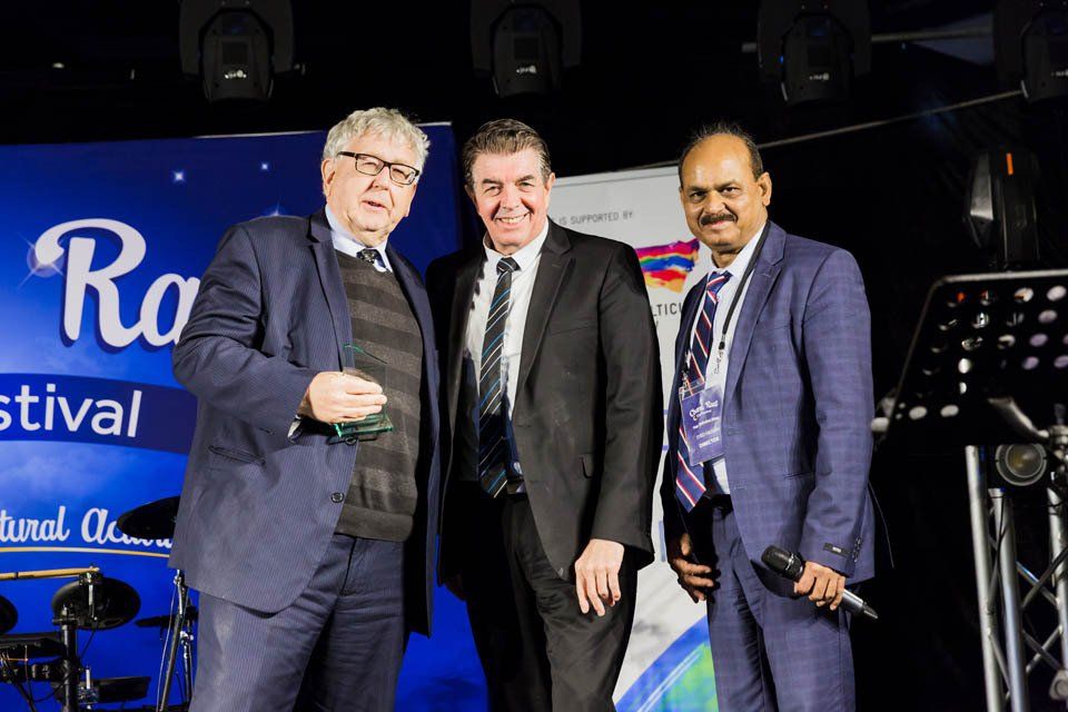 Three men in suits and ties are standing next to each other on a stage.