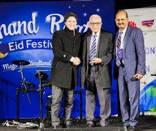 Three men in suits and ties are standing next to each other on a stage.