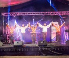 A group of people are standing on a stage holding hands.