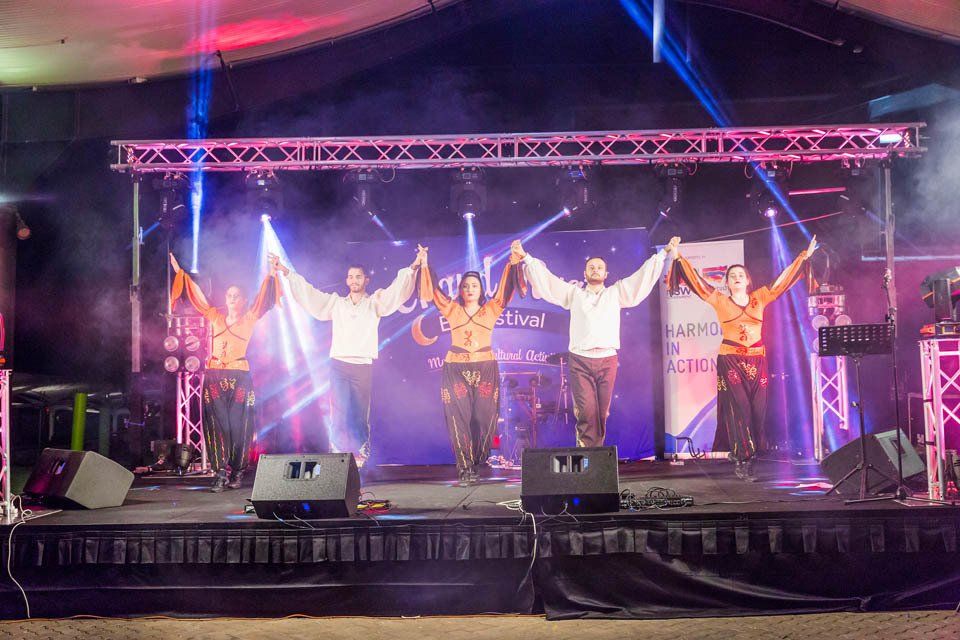 A group of people are dancing on a stage holding hands.