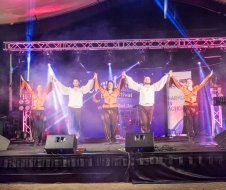 A group of people are standing on a stage holding hands.