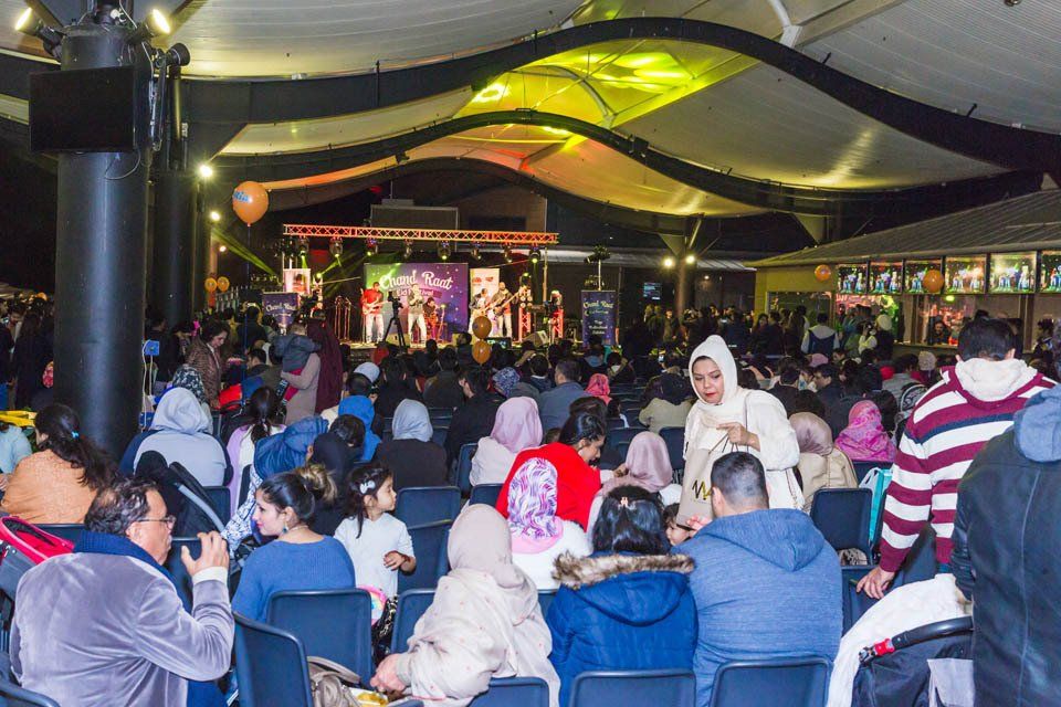 A crowd of people are sitting in chairs in front of a stage at a concert.