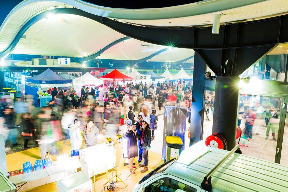 A van is parked in front of a crowd of people at a market.