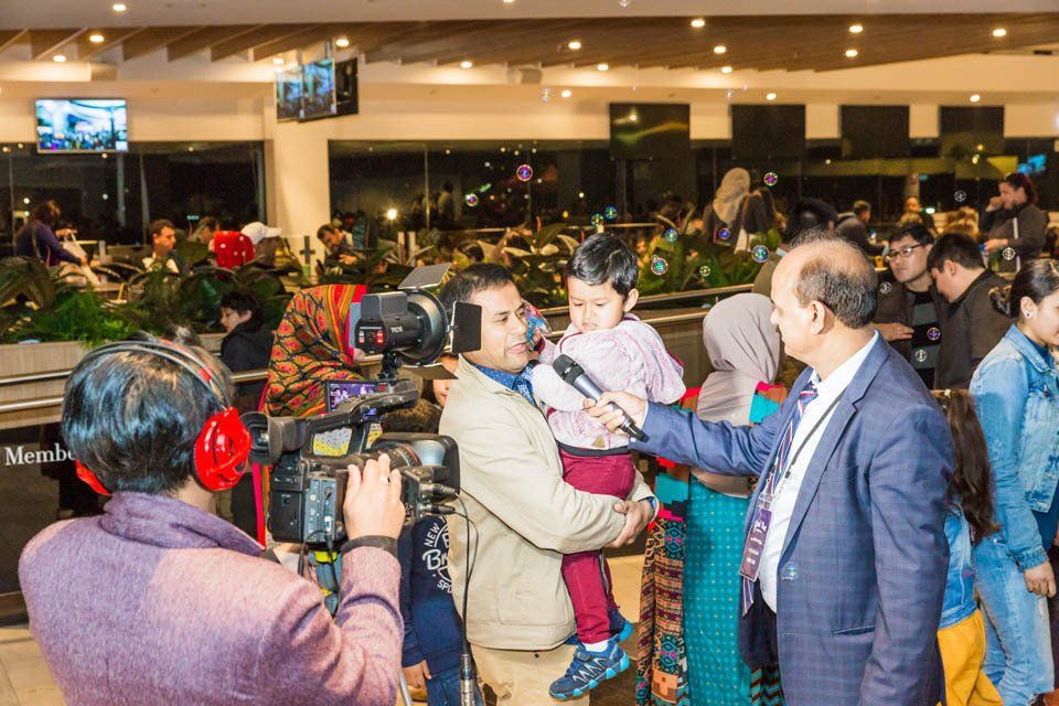 A man is holding a baby while being interviewed by a cameraman.
