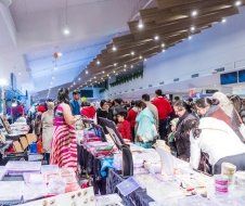 A large group of people are standing around tables at a market.